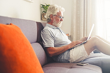 Senior man using laptop on sofa