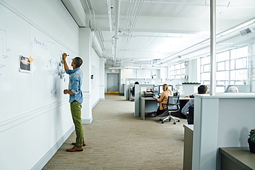 Man writing on whiteboard in office