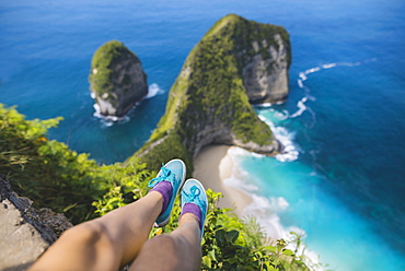 Legs of woman sitting above Kelingking Beach in Nusa Penida, Indonesia