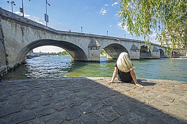 Woman sitting by bridge over Seine River in Paris, France