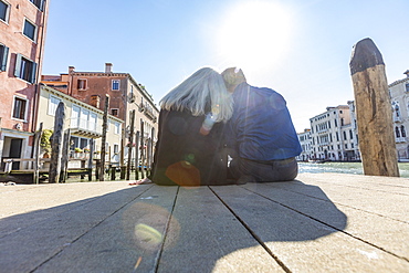 Couple sitting on jetty on Grand Canal in Venice, Italy