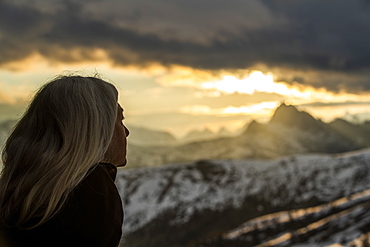 Mature woman by mountains at sunset in Dolomites, Passo Giau, Belluno, Italy