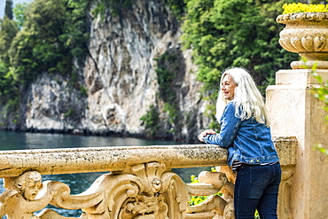 Woman leaning on balustrade at Villa del Balbianello by Lake Como, Italy