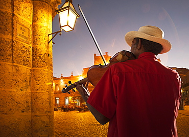 Senior man playing violin at night in Plaza de la Catedral, Havana, Cuba