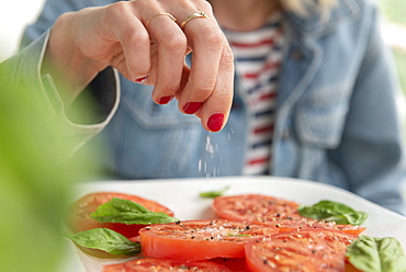 Woman sprinkling salt on tomatoes