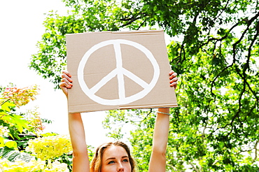 Young woman holding aloft peace symbol