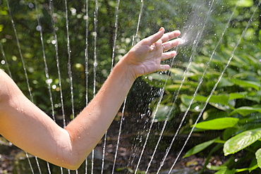 Woman's hand touching spray from sprinkler