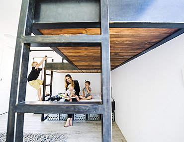 Mother reading story to children on bunk bed