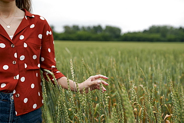 Woman wearing red polka dot shirt in wheat field