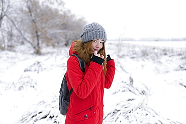 Teenage girl wearing red coat and grey hat in snow