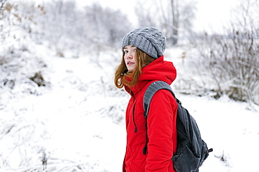 Teenage girl wearing red coat and grey hat in snow