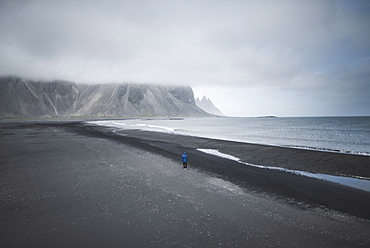 Man walking on black sand beach in Kirkjubµjarklaustur, Iceland