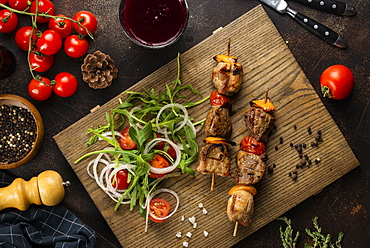 Grilled meat skewers and salad on cutting board