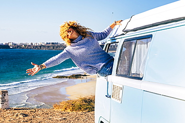 Woman leaning out of camper van window by beach in Fuerteventura, Canary Islands