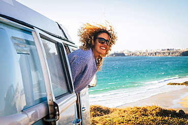 Smiling woman leaning out of camper van by beach in Fuerteventura, Canary Islands