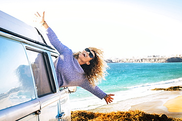 Woman leaning out of camper van window by beach in Fuerteventura, Canary Islands