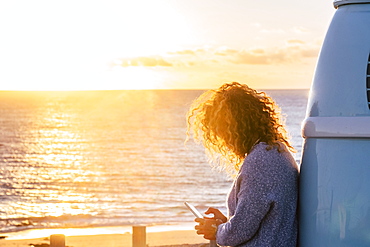 Woman using smart phone by beach at sunset in Fuerteventura, Canary Islands