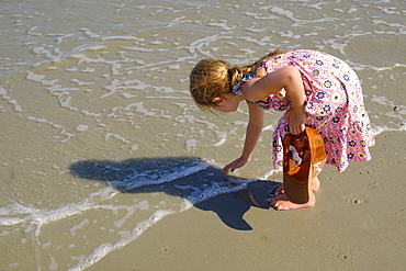 Girl bending over on beach