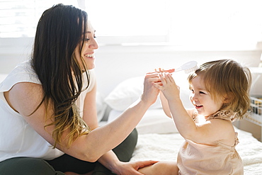Mother and daughter on bed with hairbrush