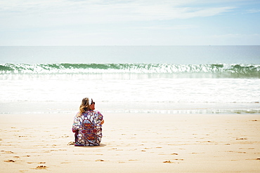 Woman sitting on beach in Lisbon, Portugal