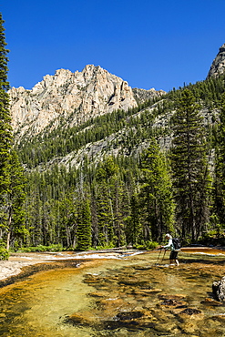 Woman wading through river by Sawtooth Mountains in Stanley, Idaho, USA