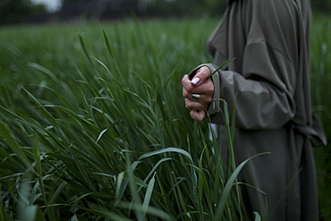 Woman wearing green coat walking through field