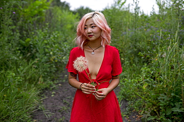 Young woman wearing red dress holding seed head