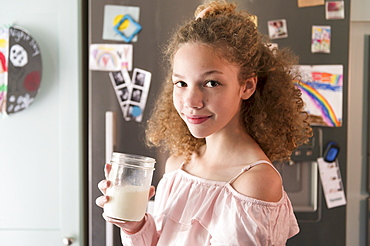 Girl holding glass of milk in kitchen