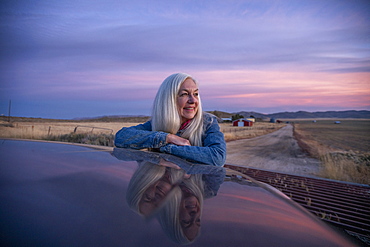 Woman leaning on car at sunset in Boise, Idaho, United States of America