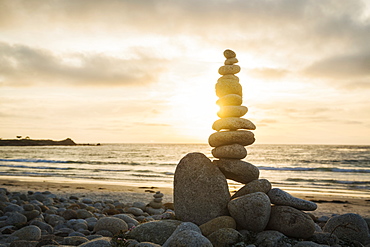 Stacked stones on beach at sunset