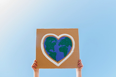 Young environmental activist holding sign against blue sky