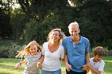 Family smiling and holding hands by trees