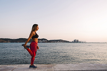 Woman stretching by sea, Lisboa, Lisbon, Portugal