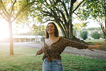 Smiling woman with her arms outstretched in park, Lisboa, Lisbon, Portugal