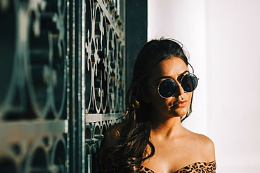 Woman wearing sunglasses by metal gate