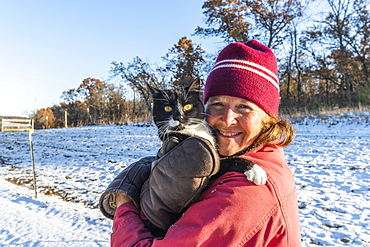 Woman holding cat in snow, Mount Horeb, Wisconsin, USA