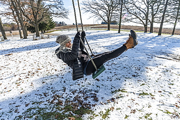 Woman on swing in snow, Mount Horeb, Wisconsin, USA