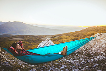 Man lying on hammock in mountain range