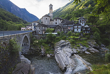 Bell tower by bridge and river in Ticino, Switzerland