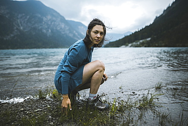 Young woman crouching by lake