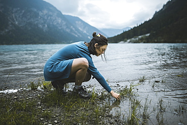 Young woman crouching by lake