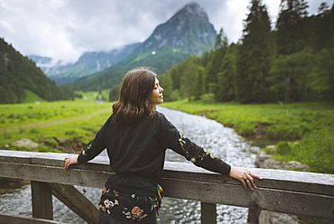 Young woman leaning on railing by river