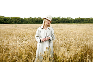 Young woman with fedora in wheat field