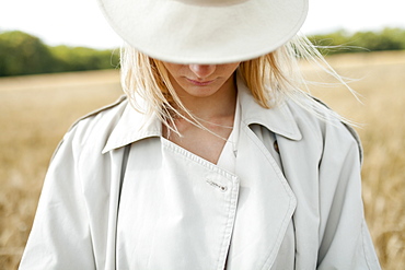 Young woman with fedora in wheat field