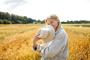 Young woman with fedora in wheat field