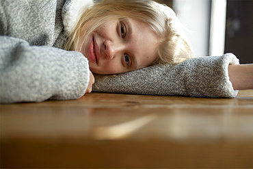 Young woman in wool coat lying on cafe table