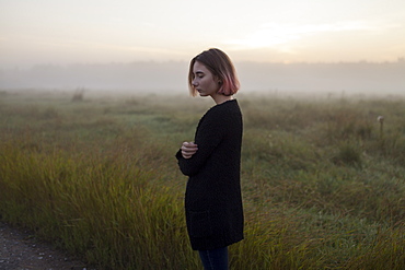 Young woman in field at sunset