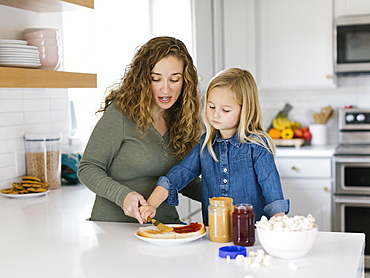 Woman making peanut butter and jelly sandwich with her daughter