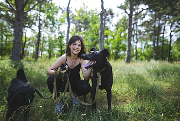 Young woman walking dogs from animal shelter in pine forest