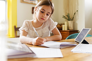 Girl (6-7) working on schoolwork at home